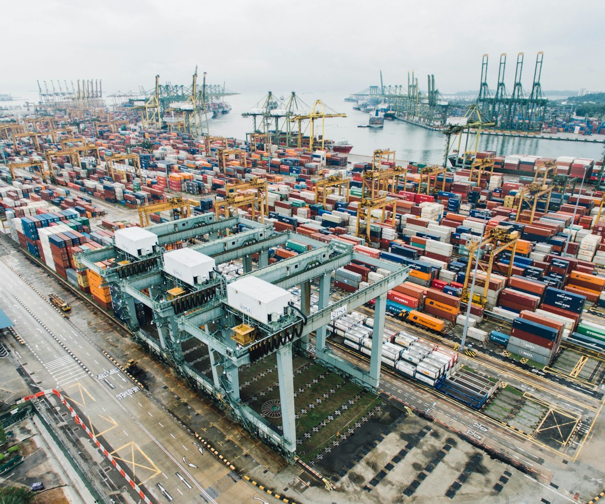 Aerial view of a container terminal with stacked shipping containers and cargo cranes